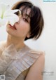 A woman holding a white flower in front of her face.