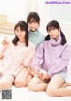 A group of three young women sitting on top of a bed.