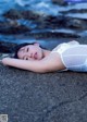 A woman laying on a rock by the ocean.