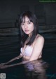 A woman in a pink bikini sitting in a pool.
