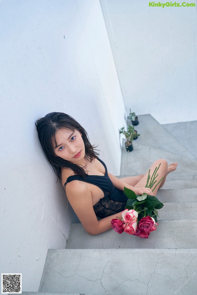A woman sitting on the steps of a building holding a bouquet of flowers.