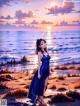 A woman in a blue dress standing on a beach.