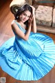 A woman in a blue dress sitting on the floor.