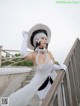 A woman in a white dress and hat posing for a picture.