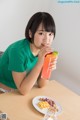 A young girl sitting at a table with a plate of food and a drink.