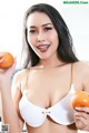 A woman in a white bra holding two oranges.