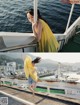 A woman in a yellow dress is standing on a boat.