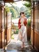 A woman in a red kimono standing in an open doorway.