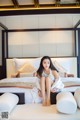 A woman sitting on a bed in a hotel room.