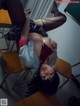 A woman laying on top of a desk in a classroom.