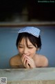 A woman in a bathtub with a blue and white polka dot hat.